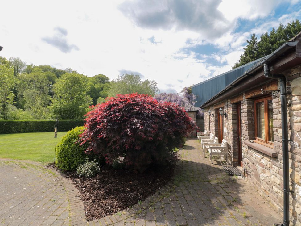 An outdoor area featuring a pathway, bush, and building at Riverside Barn in Gilwern near Crickhowell and Abergavenny