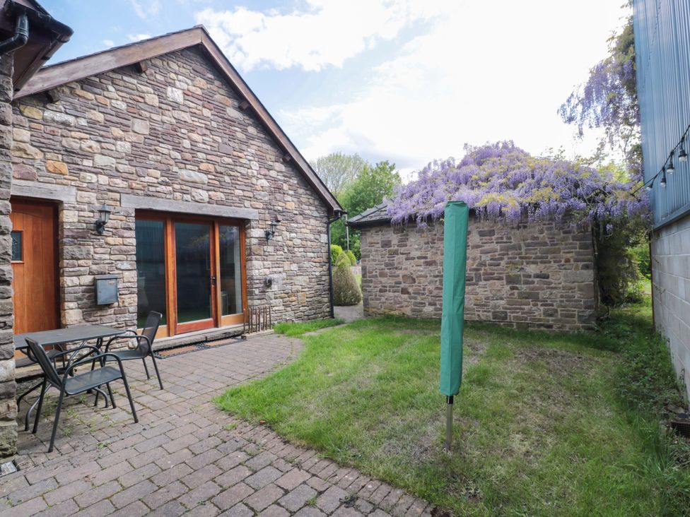 A garden with a table and chairs next to a stone house at Riverside Barn in Gilwern near Crickhowell and Abergavenny