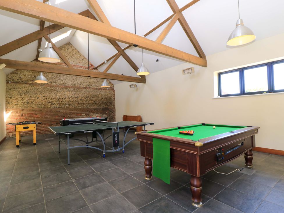 A game room with a pool table ping pong table foosball table and wooden beams on the ceiling at New Barn in Winterborne Stickland