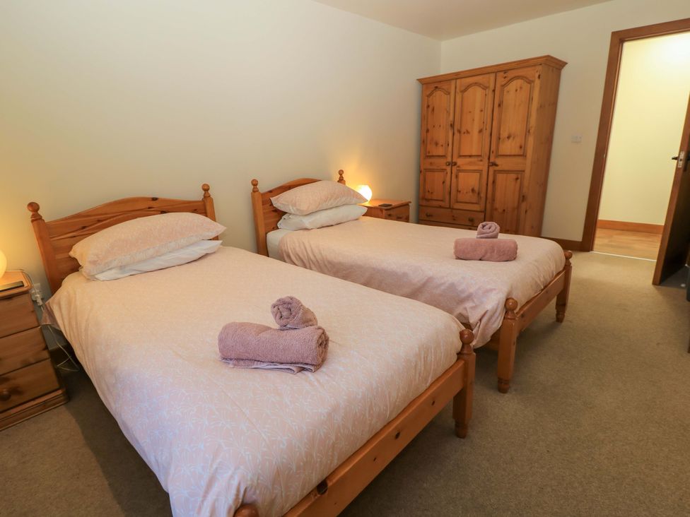 A bedroom with two single beds and wooden furniture at The Old Cart Shed in Winterborne Stickland