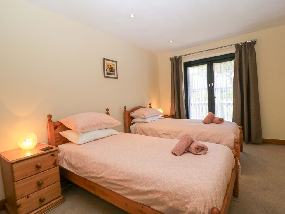 A bedroom with two single beds bedside tables and curtains at The Old Cart Shed in Winterborne Stickland