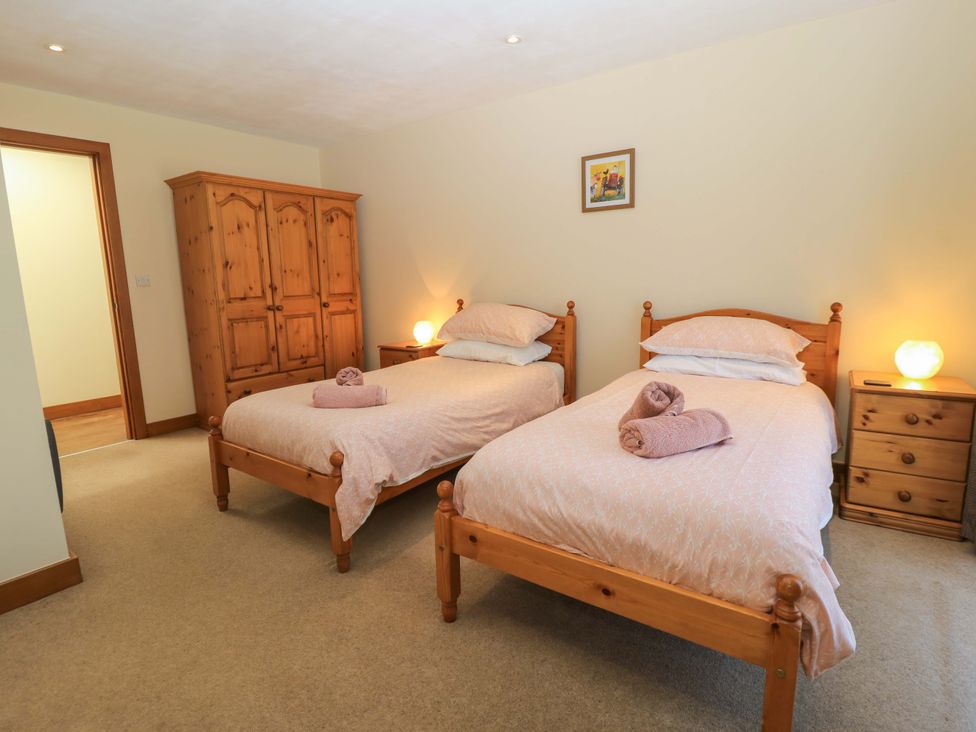 A bedroom with two single beds wooden furniture and towels on the beds at The Old Cart Shed in Winterborne Stickland