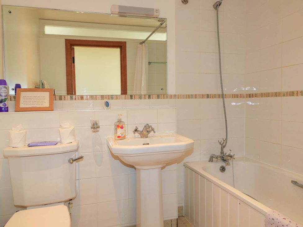 A bathroom with a toilet sink and bathtub with showerhead at The Old Cart Shed in Winterborne Stickland