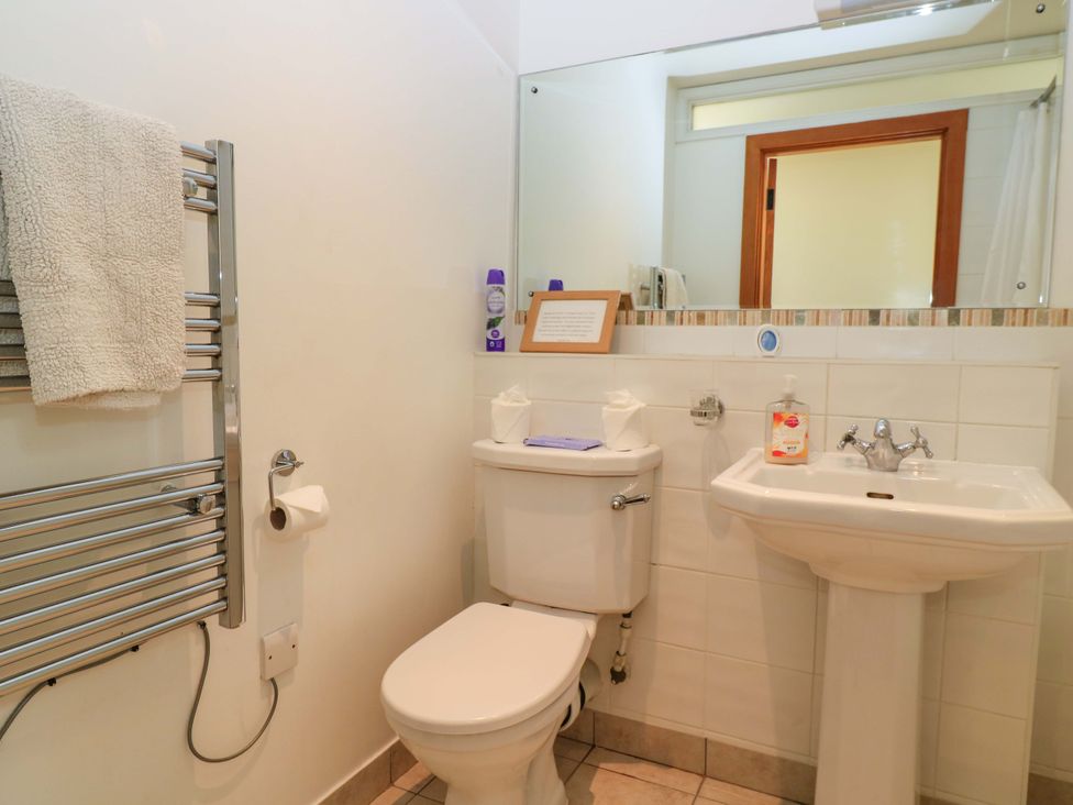 A bathroom with a toilet a sink a towel rack and a mirror at The Old Cart Shed in Winterborne Stickland