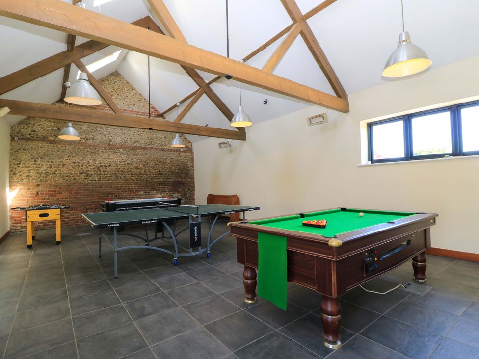 A game room with a pool table ping pong table foosball table and wooden beams at Rowdens Barn in Winterborne Stickland