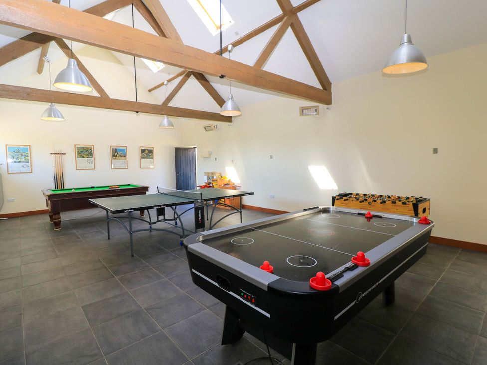 A game room with an air hockey table ping pong table pool table and foosball table at Rowdens Barn in Winterborne Stickland