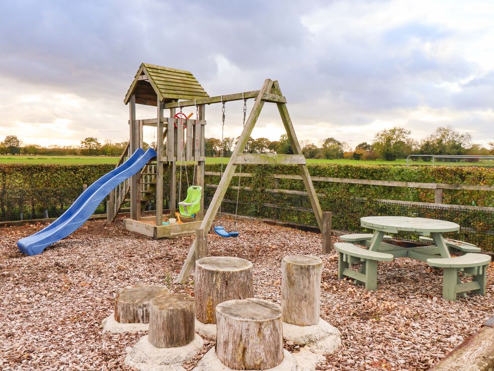 A playground with a slide and swings at Apple Tree Cottage in Dunnington