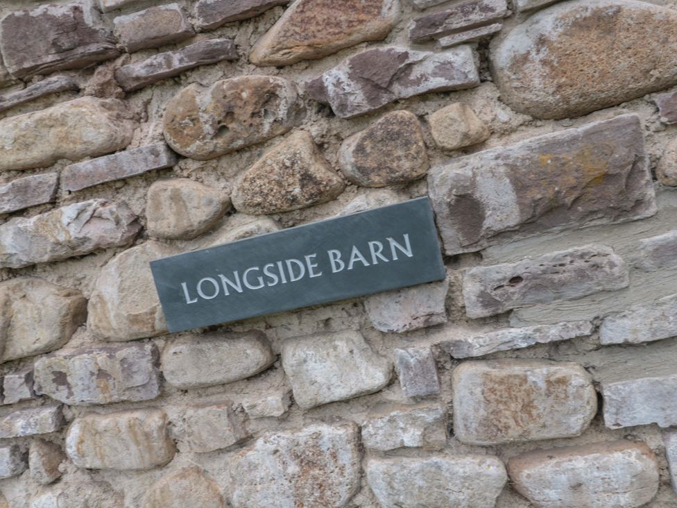 A stone wall with a plaque reading Longside Barn in Gilwern