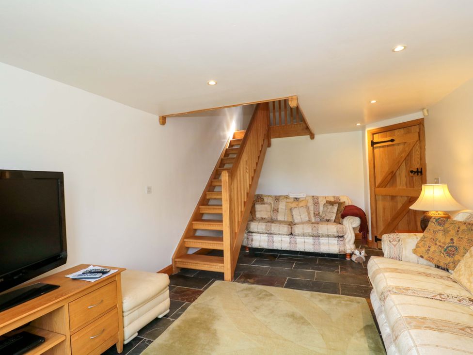 A living room with a television and sofa at Longside in Gilwern