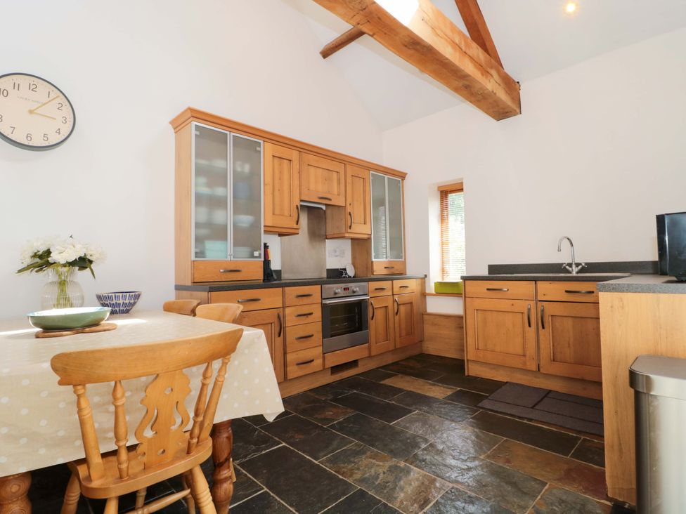 A kitchen with wooden cabinets and a table at Longside in Gilwern