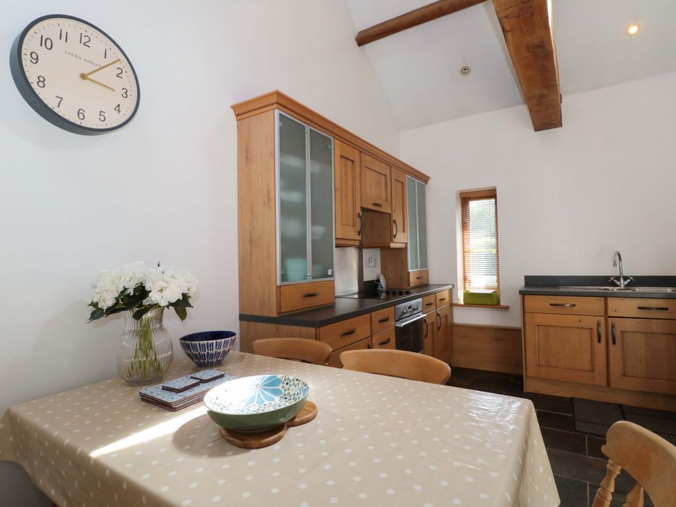 A kitchen with a dining table and a clock at Longside in Gilwern