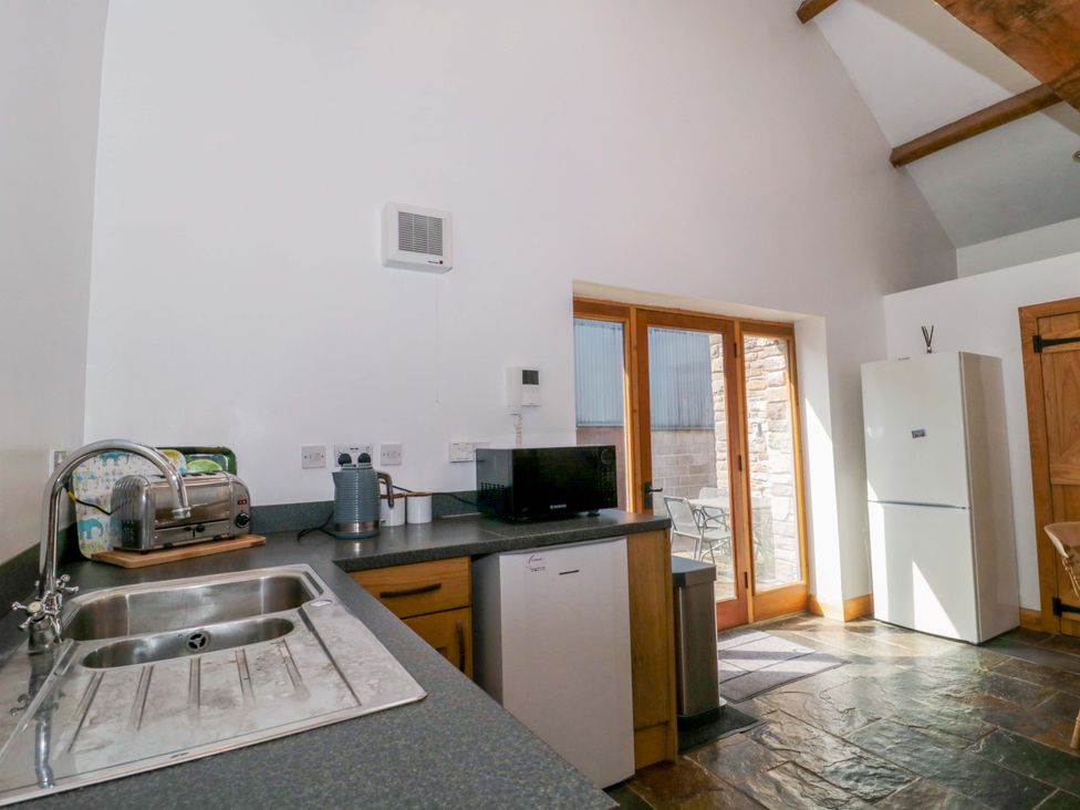 A kitchen with a sink, refrigerator, and appliances at Longside in Gilwern