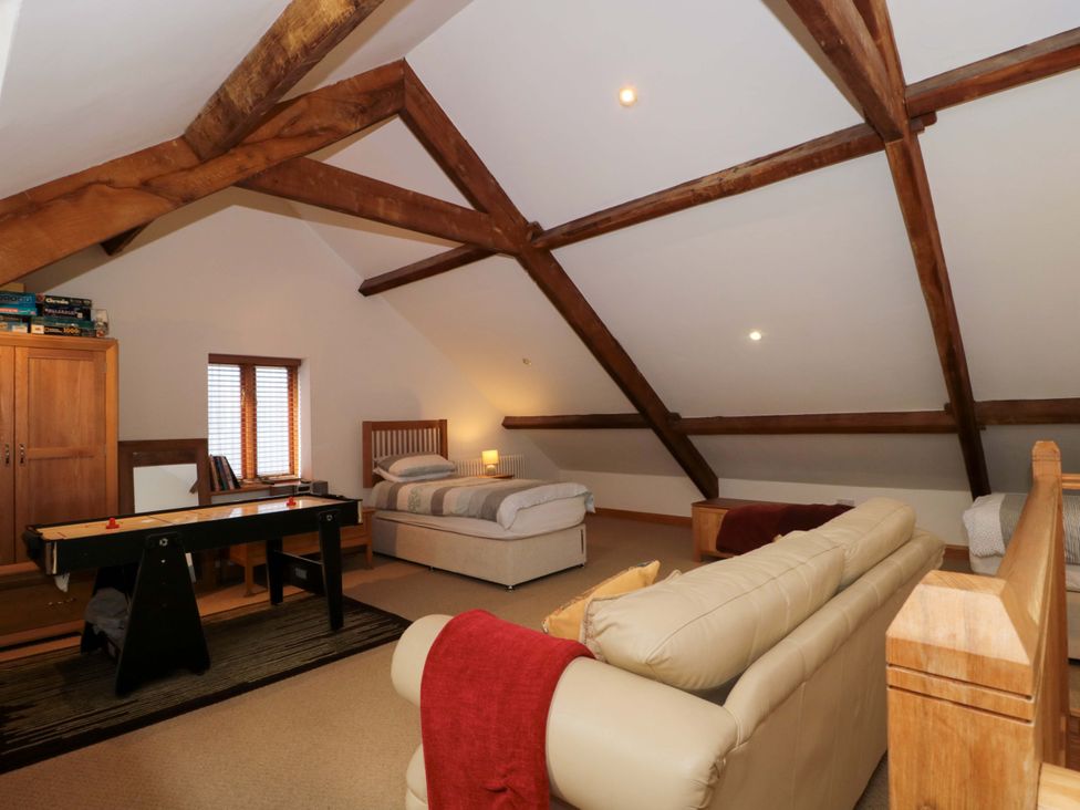 A loft with a bed and seating area at Longside in Gilwern