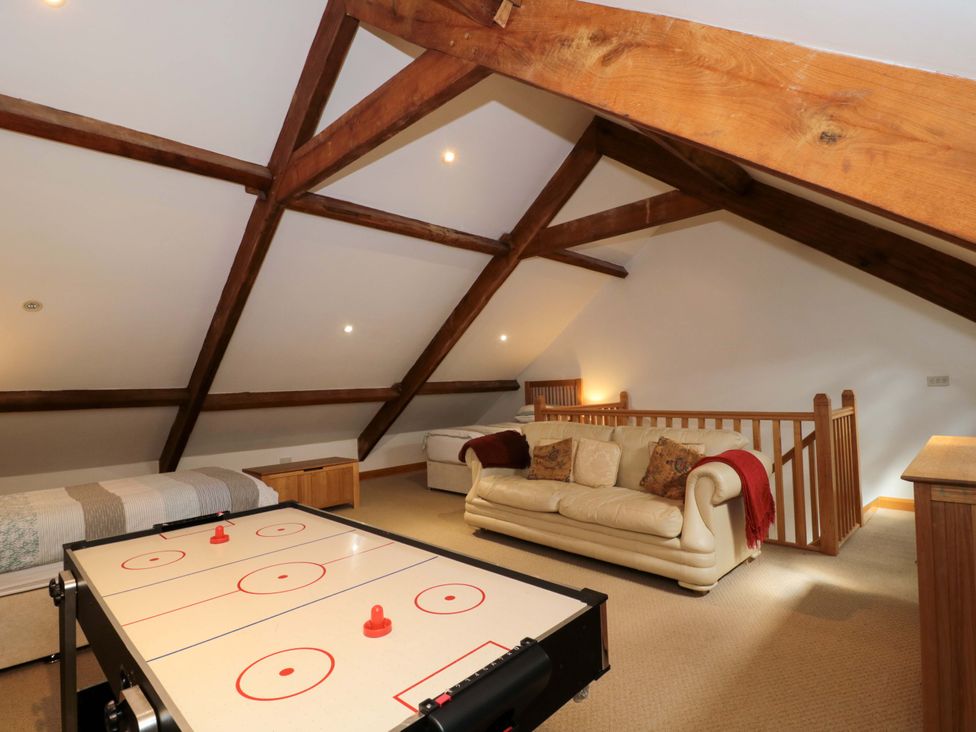 A game room with a sofa and an air hockey table at Longside in Gilwern