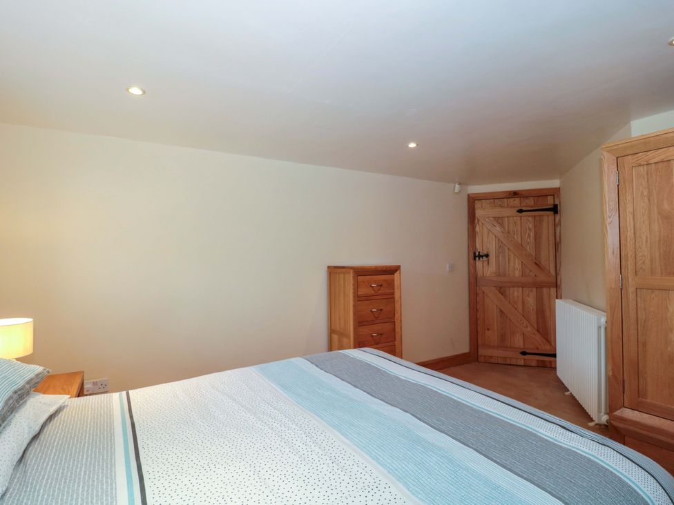 A bedroom with a bed and dresser at Longside in Gilwern