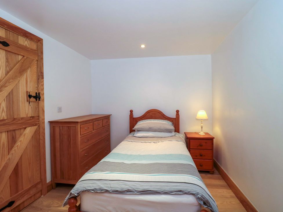 A bedroom with a bed and dresser at Longside in Gilwern