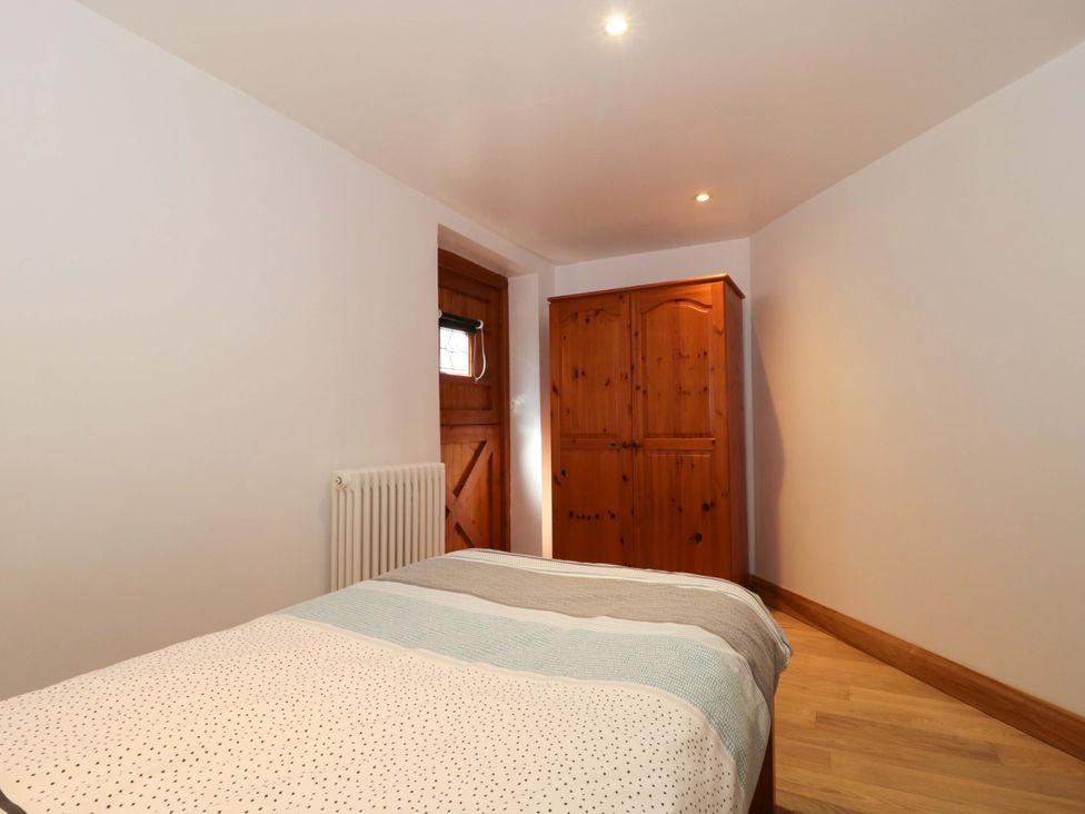 A bedroom with a bed and a wardrobe at Longside in Gilwern