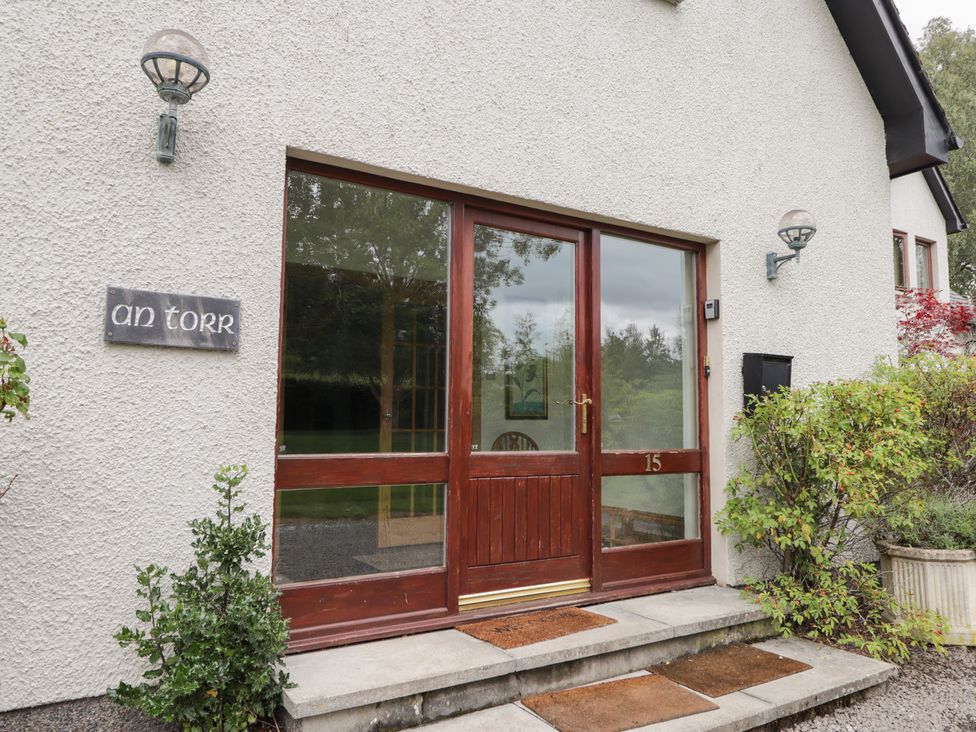 Entrance with a wooden door and sign at An Torr in Newtonmore