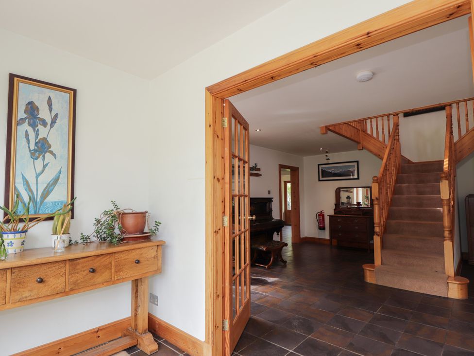A hallway with a staircase and console table at An Torr, Newtonmore