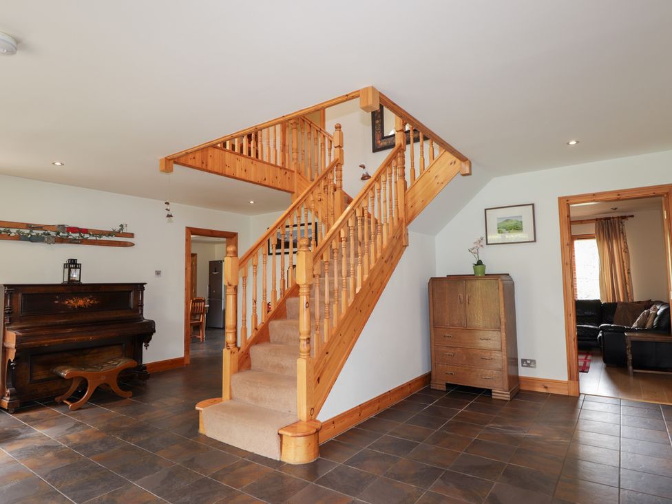 A hallway with a staircase and a piano at An Torr in Newtonmore