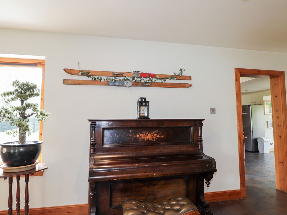 A living room with a piano and skis on the wall at An Torr in Newtonmore