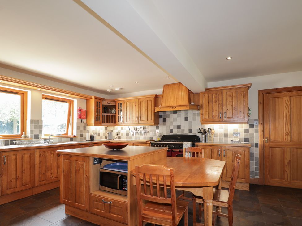 A kitchen with wooden cabinets and a dining table at An Torr in Newtonmore