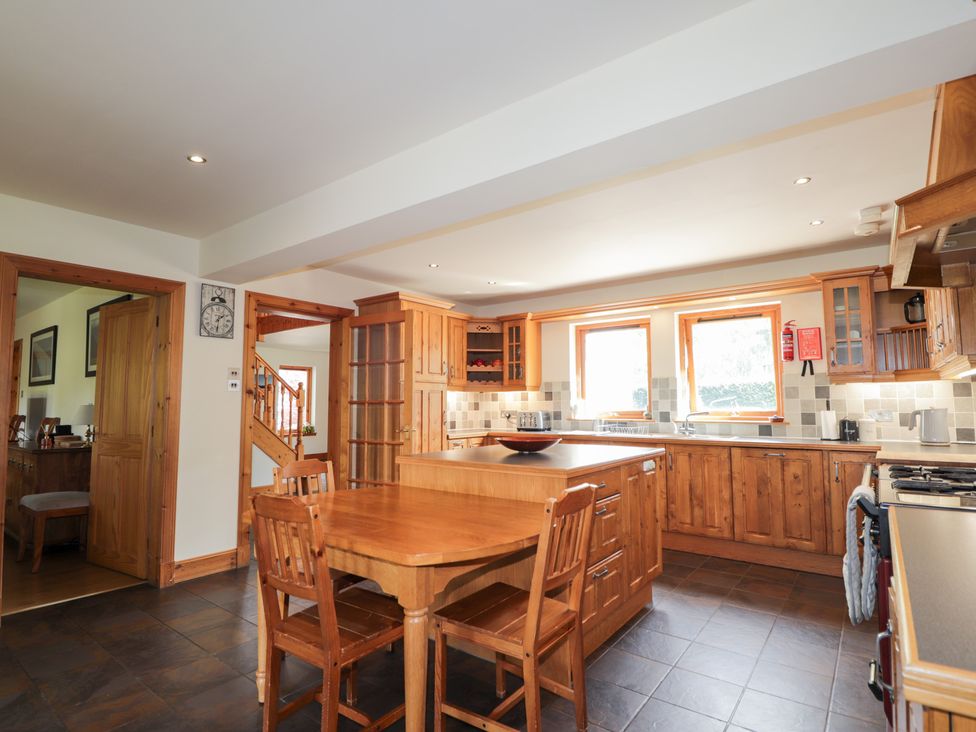 A kitchen with wooden cabinets and a dining table at An Torr, Newtonmore