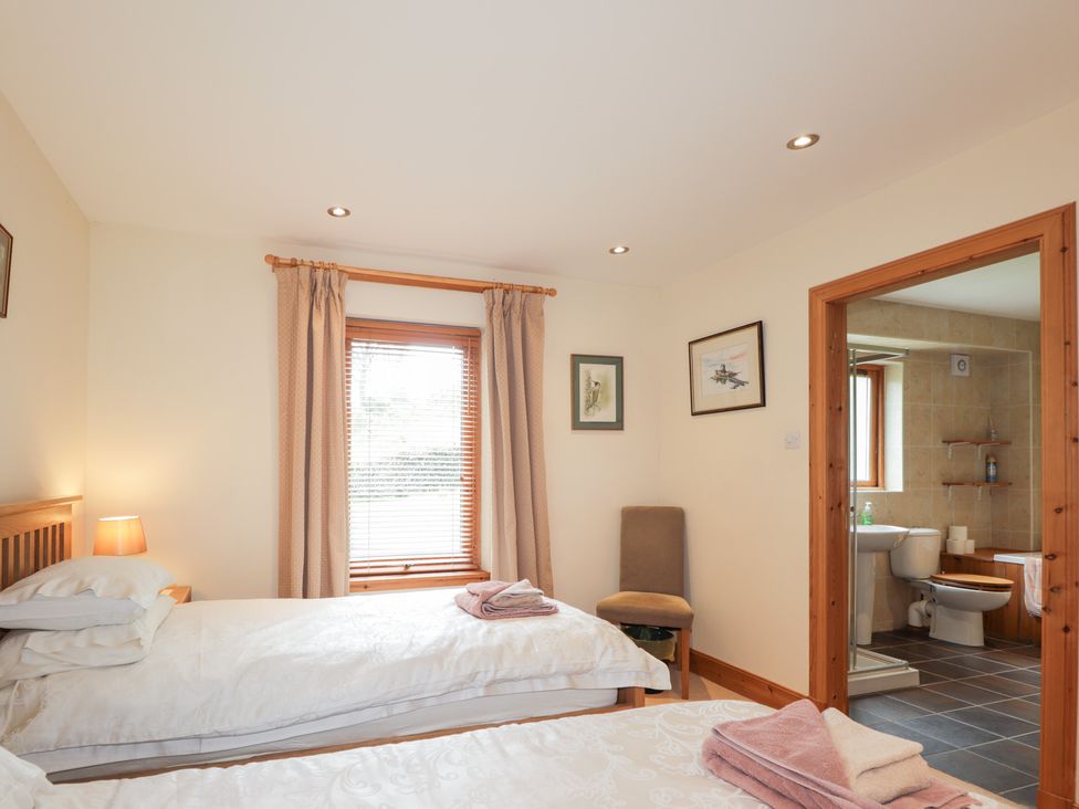 A bedroom with two beds and an attached bathroom at An Torr in Newtonmore