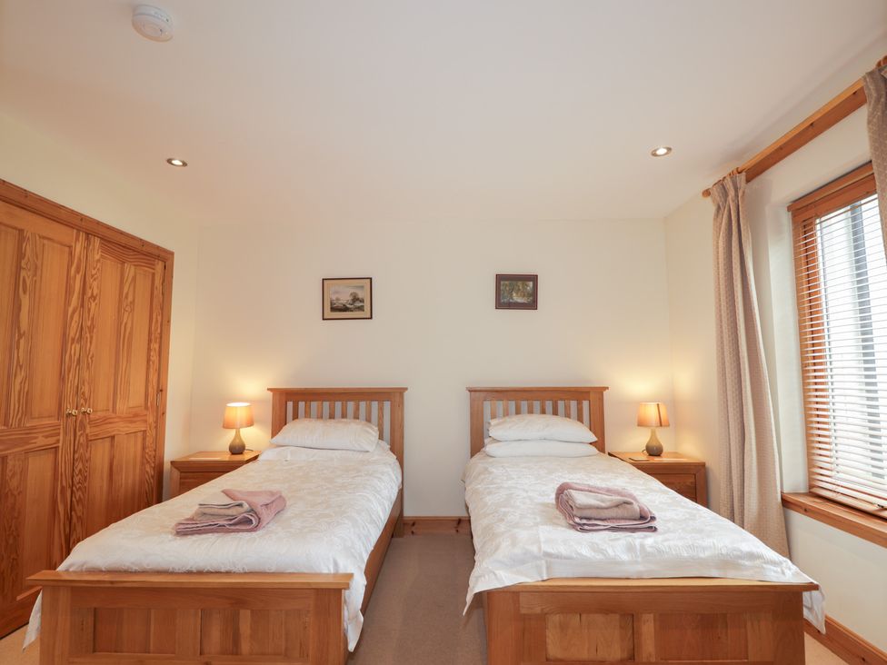 A bedroom with twin beds and lamps at An Torr in Newtonmore