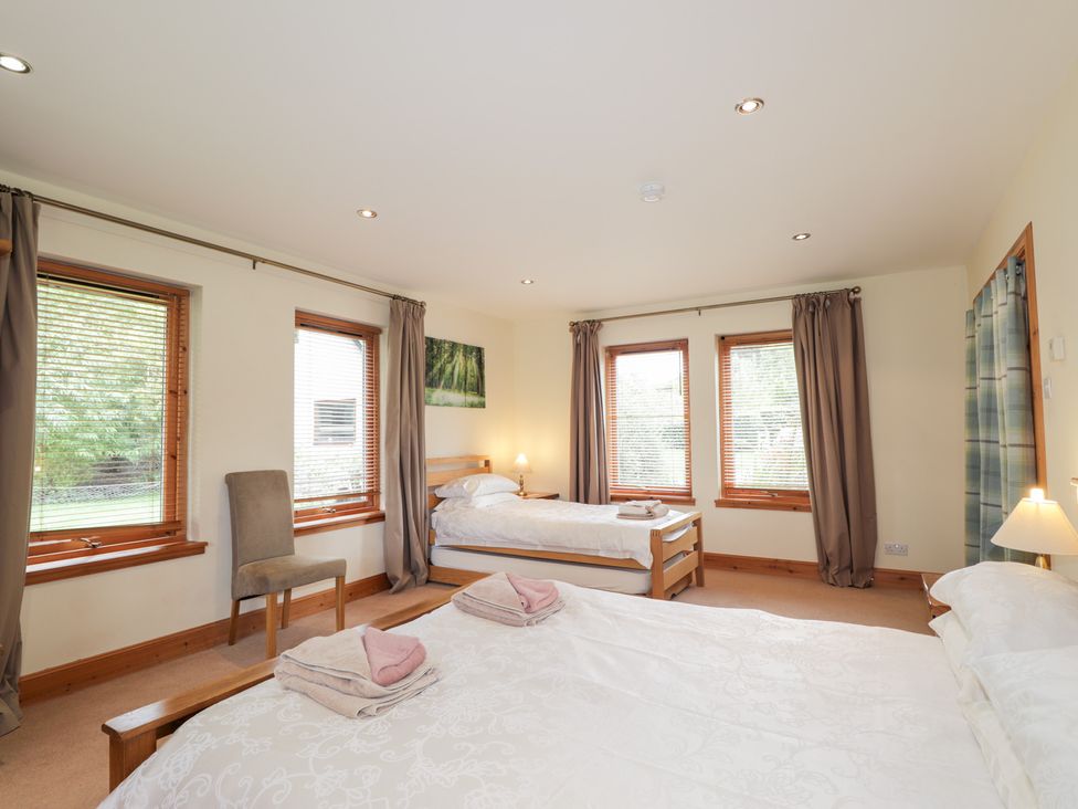A bedroom with two beds and a chair at An Torr in Newtonmore