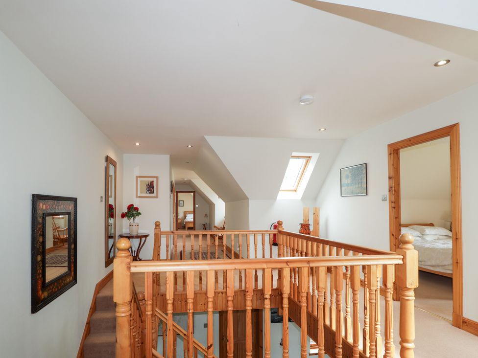 A hallway with a wooden railing and framed mirrors at An Torr in Newtonmore