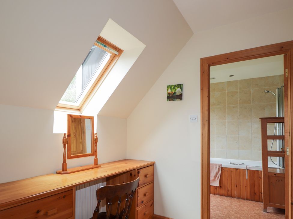 A room with a vanity table and mirror leading to a bathroom at An Torr in Newtonmore