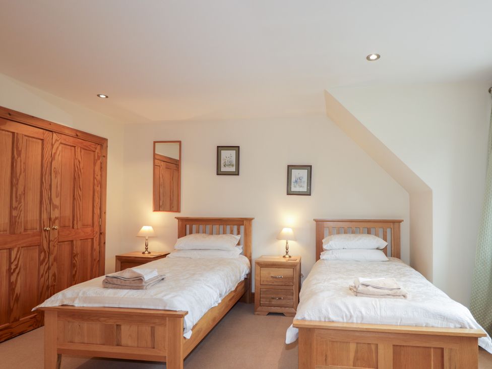 A bedroom with two single beds and wooden furniture at An Torr in Newtonmore