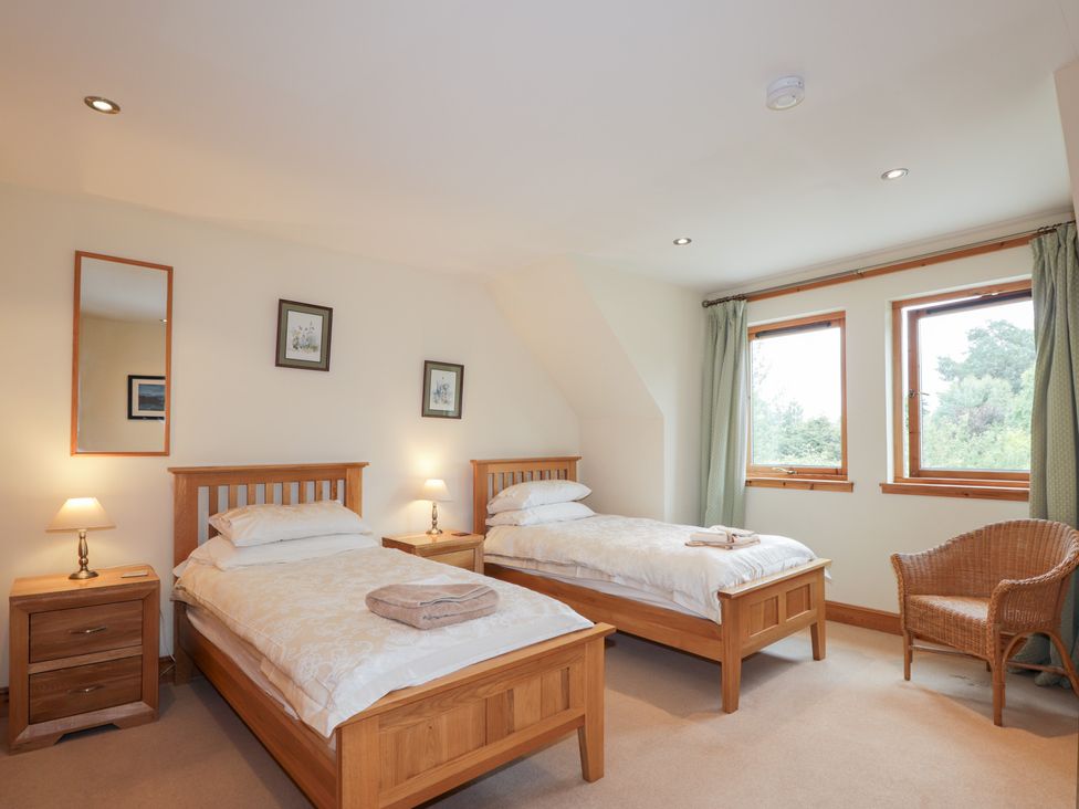 A bedroom with two beds and a chair at An Torr in Newtonmore