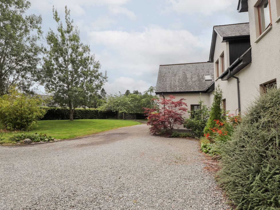 An outdoor area with a gravel driveway and trees at An Torr in Newtonmore