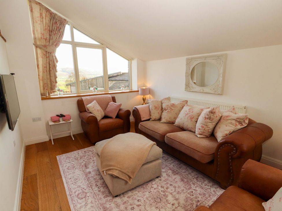 A living room with a sofa and television at Hawkrigg Cottage in Kirkby Lonsdale
