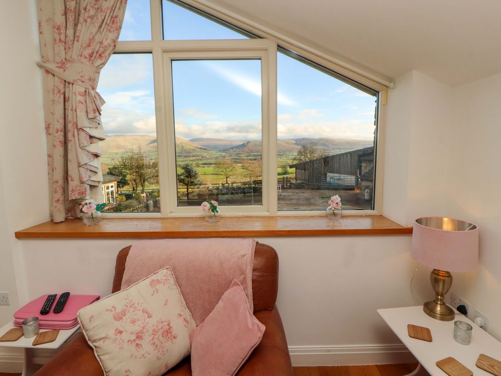 A living room with a window overlooking the countryside at Hawkrigg Cottage in Kirkby Lonsdale