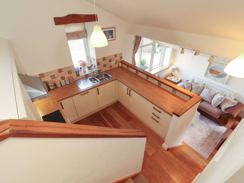 A kitchen with a counter, sink, and sofa at Hawkrigg Cottage in Kirkby Lonsdale