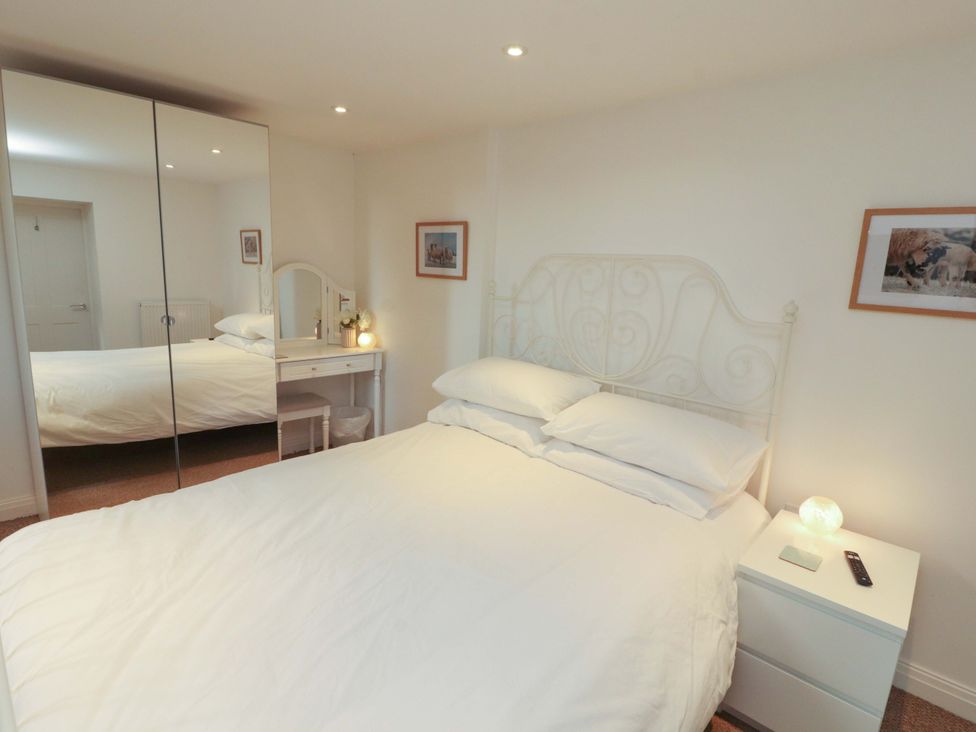 A bedroom with a bed and nightstand at Hawkrigg Cottage in Kirkby Lonsdale