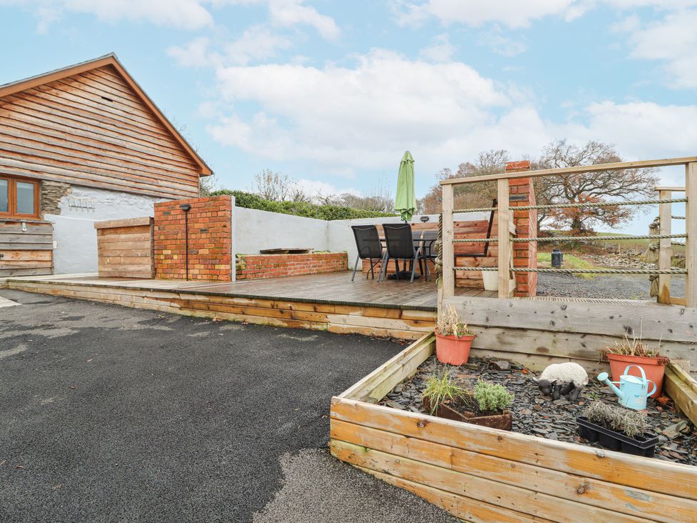 An outdoor area with a deck, table and chairs at Rhianwen, Plas Moelfre Hall Barns Llanrhaeadr-ym-Mochnant