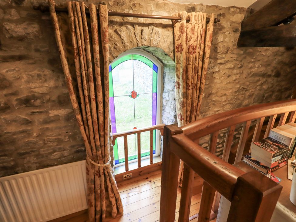 A loft with a stained glass window and books at The Stables in Horton-in-Ribblesdale near Settle