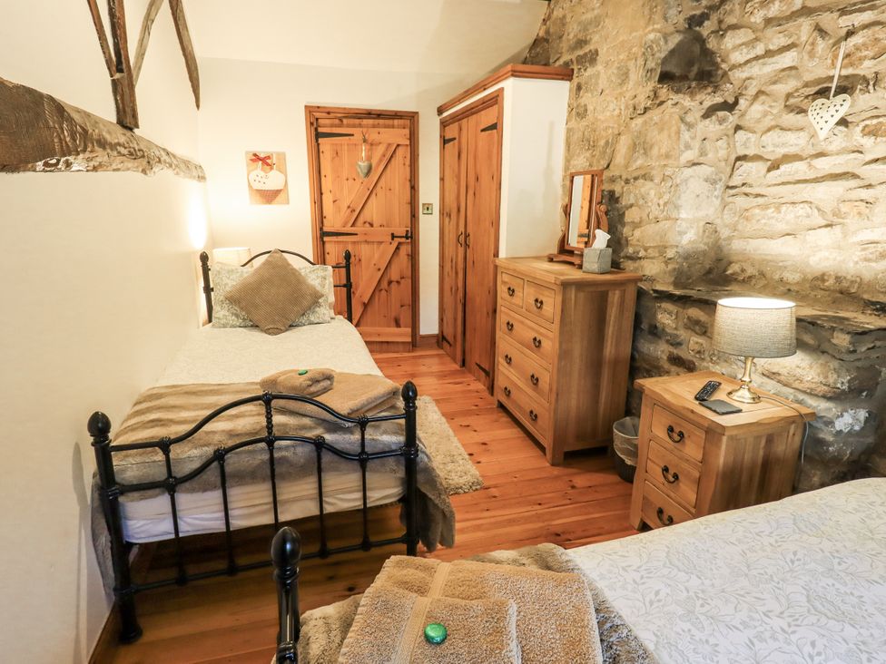 A bedroom with two single beds and wooden furniture at The Stables in Horton-in-Ribblesdale near Settle