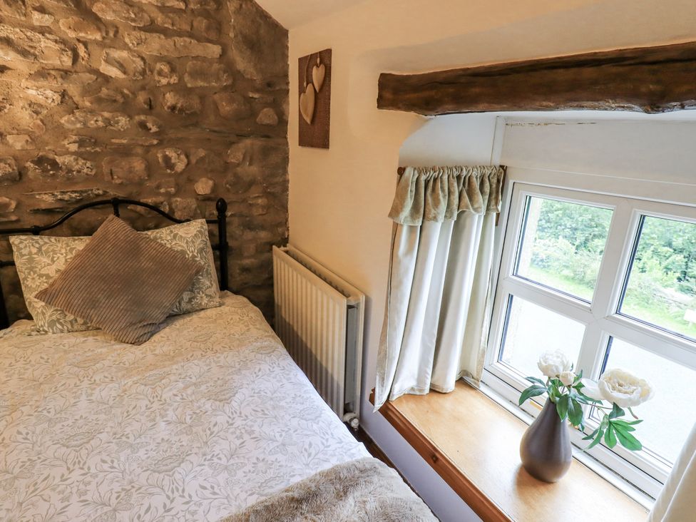 A bedroom with a bed and window at The Stables in Horton-in-Ribblesdale near Settle