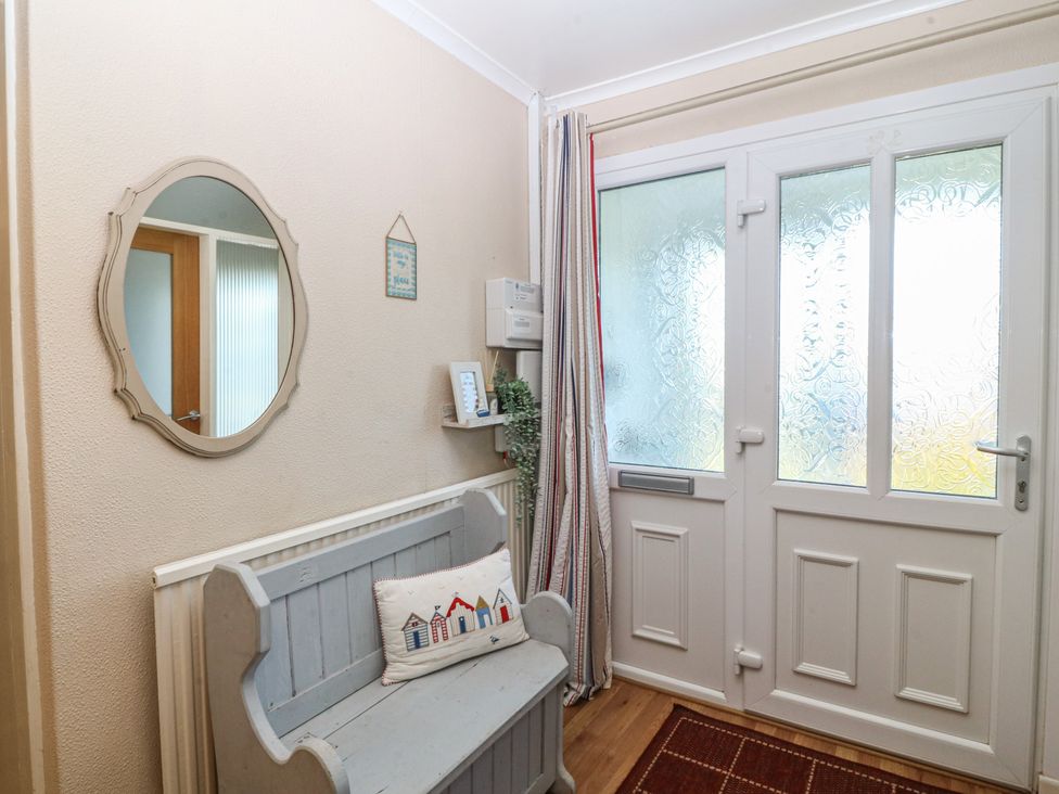 A hallway with a bench and mirror at Salty Puffin in Benllech