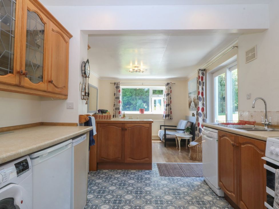 A kitchen with appliances and furniture at Salty Puffin in Benllech