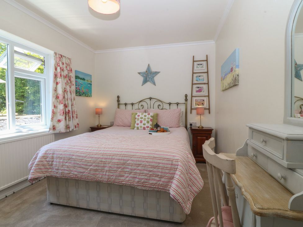 A bedroom with a bed and bedside table at Salty Puffin in Benllech