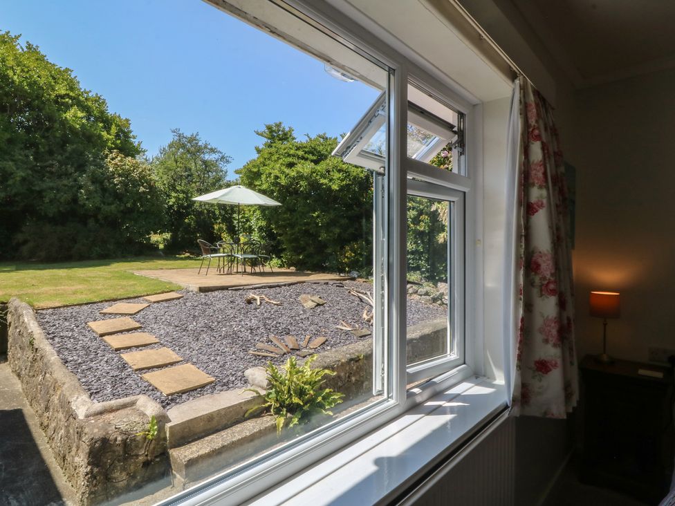 A view from a window showing a garden with a table and chairs at Salty Puffin in Benllech
