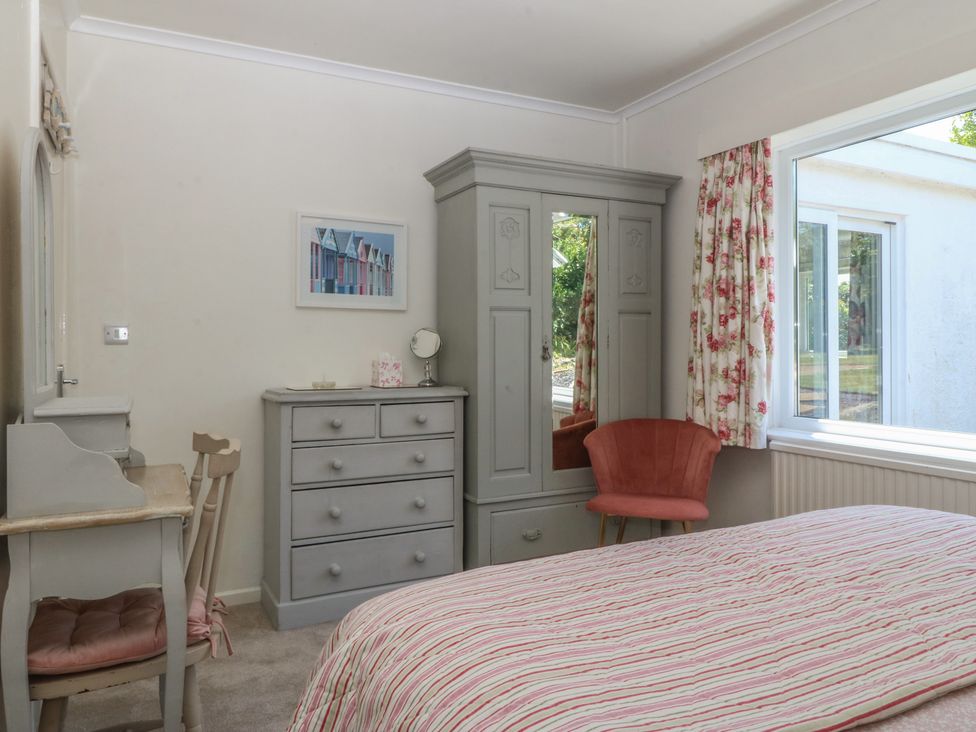 A bedroom with a bed and wardrobe at Salty Puffin in Benllech