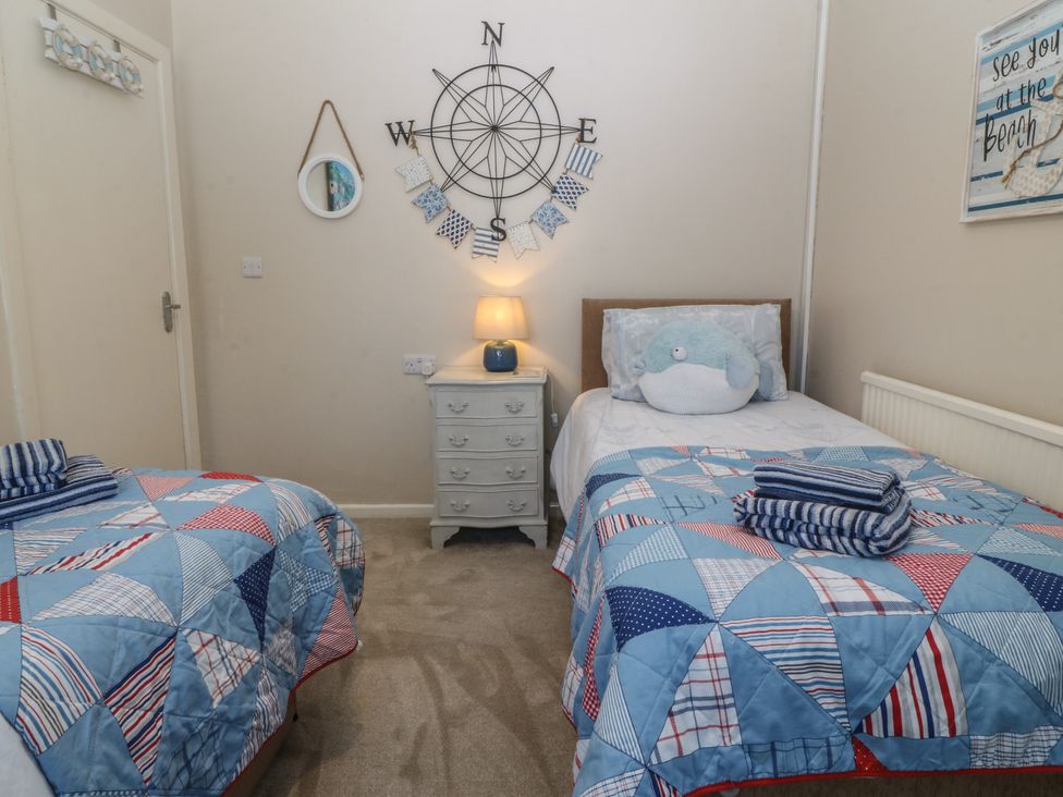 A bedroom with two single beds and a chest of drawers at Salty Puffin in Benllech