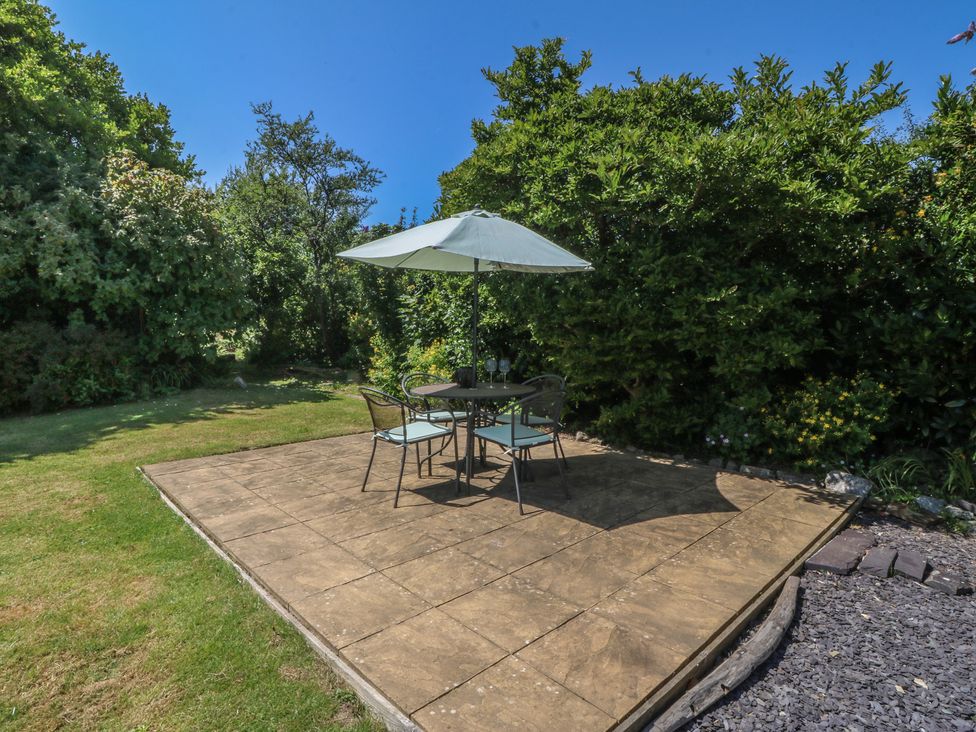 A garden with a table and chairs under an umbrella at Salty Puffin in Benllech